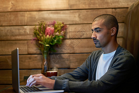 这家咖啡馆是他找到一点安宁的地方 一个年轻人在咖啡店的笔记本电脑上工作图片