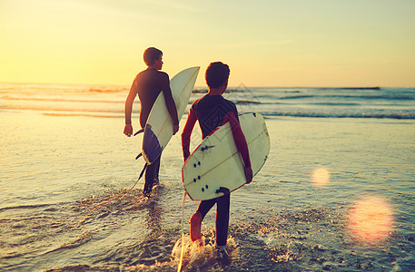 那些海浪不会骑着自己 两个年轻的兄弟带着他们的冲浪板 滑入大海中去图片
