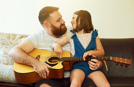 谁比大师本人更值得学习 一个可爱的小女孩在家里和她父亲一起弹吉他图片