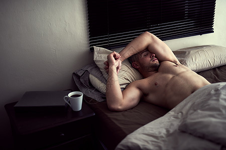 早起的鸟今天可以留住虫子 一个不穿衬衫的年轻人睡在他的床上图片