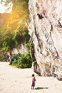 悬崖 两个年轻人在阳光明媚的一天攀岩图片
