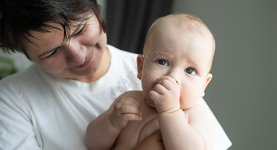 一位年轻的母亲抱着她刚出生的婴儿 哺乳婴儿的母亲 母亲母乳喂养她的孩子 家人在家 一个幸福的母亲和孩子的肖像女儿卧室护理喜悦尿布图片