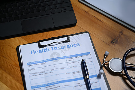 健康保险的表格和听诊器放在木制桌子上 健康保险的概念图片