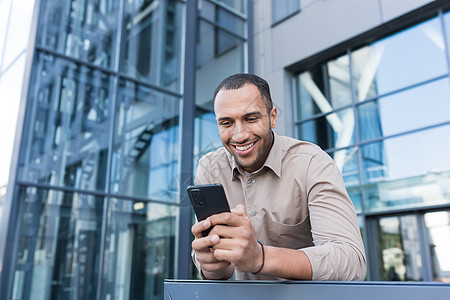 现代办公大楼外的成功商务人士使用智能手机 阅读信息和浏览网页的人 穿着衬衫的非洲裔美国人手持电话打字信息图片
