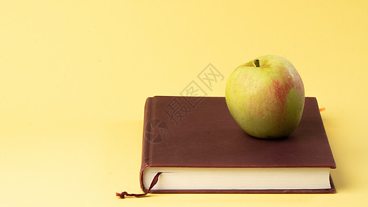 黄背景的书和苹果 学习 秋天图片