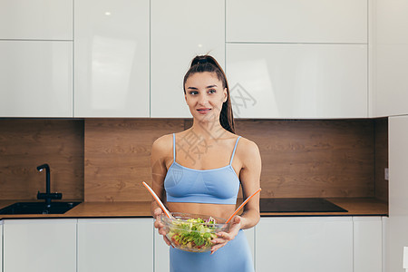 年轻美丽的女性营养学家 展示现成新鲜蔬菜沙拉 看着相机 微笑着笑容健康饮食黄瓜饮食幸福厨房家庭生活快乐家庭烹饪食品图片
