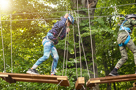 冒险攀登高空钢丝公园  儿童课程绳索公园 绳索公园绳索桥上可爱小女孩的画像幸福木头享受挑战平衡高度危险乐趣行动绳索图片