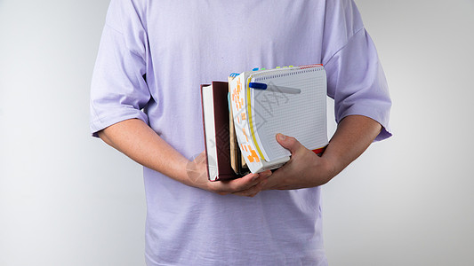 一个手拿着教科书和笔记本的学生 以白人背景参加班级特写课目图片