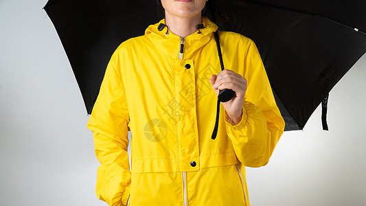 穿黄色雨衣的女人 在白色背景上拿着黑色的雨伞配饰夹克天气季节下雨风暴风衣衣服服装外套图片