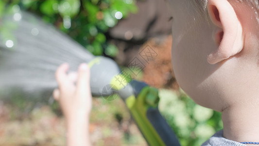 有趣的小男孩在花园房屋后院浇灌草坪植物 可爱的孩子在炎热的阳光明媚的夏天在户外玩灌溉软管 孩子们帮忙做家务 孩子们的活动 童年微图片