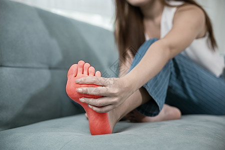 坐在沙发上的亚洲年轻女性 握着她的脚和伸展的肌肉 有症状女士保健修脚身体扭伤治疗疾病药品女孩长椅图片