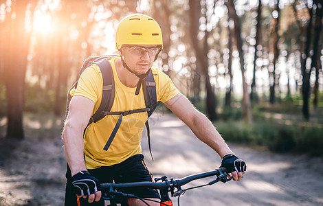 在阳光明媚的森林里骑自行车的男人图片