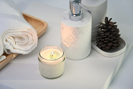 在白桌上燃烧芳香蜡烛 毛巾和瓶子 斯帕成分和健康概念图片