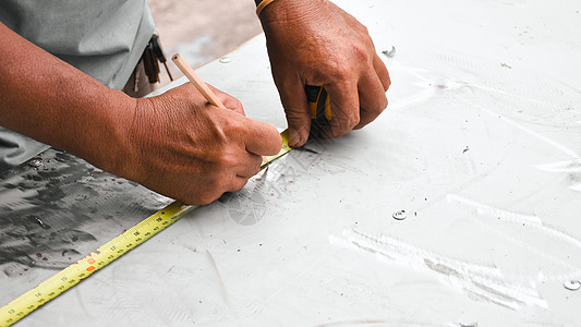 技术员用测量磁带测量金属板的长度 并用铅笔在工厂中写出距离和钢笔图片