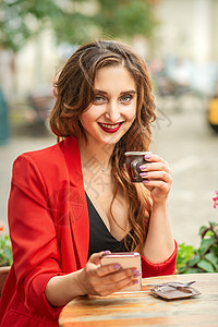 穿红外套的年轻游客女子 在咖啡厅户外的餐桌上喝咖啡杯旅行酒店假期桌子制作者头发咖啡店早餐成人女性图片