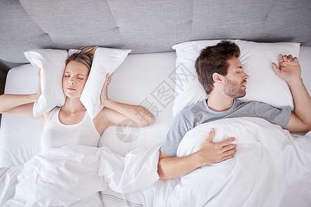 睡觉 打鼾和妻子在耳朵上放枕头以阻止有睡眠问题的丈夫在床上发出噪音 卧室里疲惫的女人躺在呼吸暂停的男人旁边 失眠 沮丧和压力图片