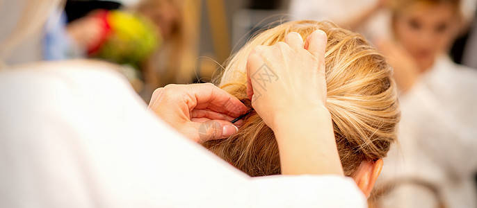 发型师的手在美容院里 对女性长发做专业造型工作刷子客户美容师发型美丽金子职业发型设计理发图片