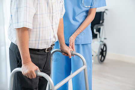 老年护理理疗师协助她满足的高级病人用折叠行走器医生照顾者治疗残障看门人康复老年保健疗法医学背景