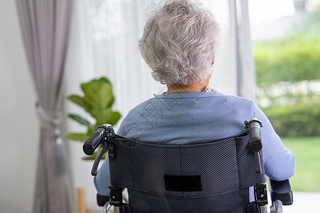 坐在轮椅上的老年妇女向窗外看望等待着某人 可悲 忧郁和沮丧的悲哀白发祖母老太婆康复女士疗养院残障人员麻痹退休图片