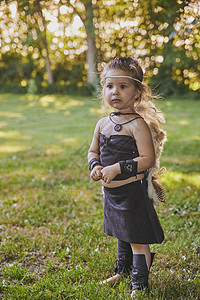 穿着原始人衣服的可爱宝宝护身符公园装饰品女儿女孩日落历史野人节日羽毛图片