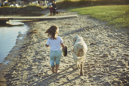 日落时在海滩上走狗的可爱孩子遛狗小狗运动婴儿童年朋友晴天友谊宠物海岸图片