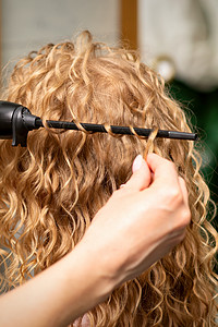 美容院后视中 年轻女人的发型画家卷发 用卷轴铁做头发卷发女孩卷发器摄影工作室冰壶滚筒发型师服务造型客户图片
