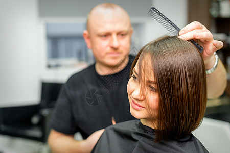 年轻的caucasian褐发女人 在一家店里由男美容师理发女孩微笑店铺黑发美容院客户女士梳妆台商业工作图片