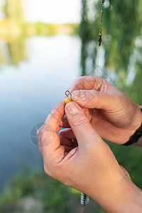 鱼饵的概念 渔夫的雄性手绳子在钓鱼杆上对蓝湖的钓鱼钩图片
