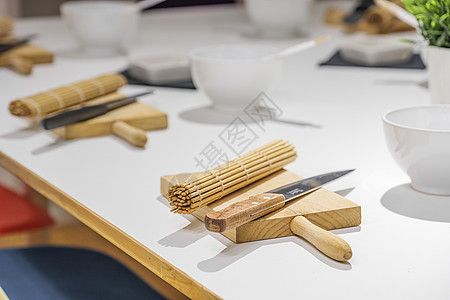 寿司大师课前 白桌上放着几套刀 木板和竹制寿司垫 教育 烹饪和娱乐理念图片