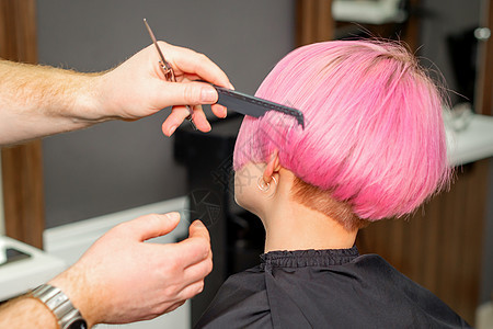梳理头发的美发师手 在美容院里 为一位年轻的天主教女子做短粉色发型女士职业护理沙龙理发化妆品工作室发型师理发师顾客图片