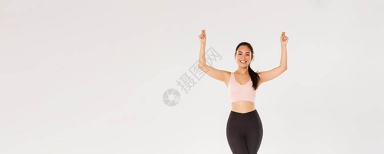全长苗条健康的亚洲微笑女孩锻炼 穿着运动服 举起手 好像拿着标语或横幅 宣传运动器材或健身房会员折扣讲师举牌子身体运动装广告标识图片