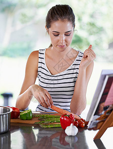 健康的生活 一个年轻女人用食谱做饭 (笑声)图片