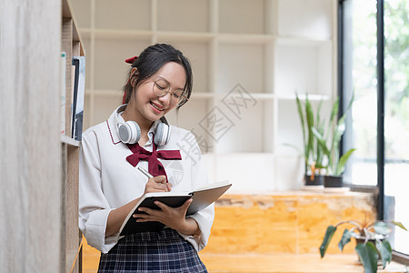 年轻女学生在图书馆工作 亚裔妇女在教科书中作笔记 男女学校作业技术写作阅读班级桌子考试记事本女孩图片