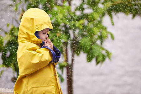 又冷又湿 一个小男孩在雨中在外面玩耍图片
