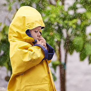 今年冬天保持防水状态 一个可爱的小男孩在雨中在外面玩耍图片