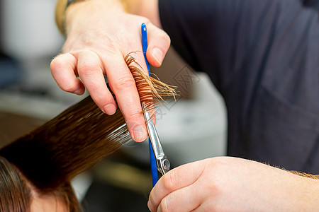 美发师的手握住手指间的发丝 在美发沙龙用梳子和剪刀为年轻女子的长发理发 特写理发师发型顾客女孩造型女性奢华造型师发型师女士图片