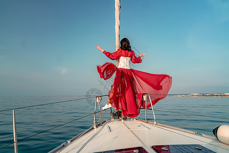 夏日在游艇上穿着红色礼服的中年女子 有吸引力的中年妇女 豪华暑假冒险 户外活动女士船长闲暇女性假期娱乐旅行海滩方向盘帆船图片