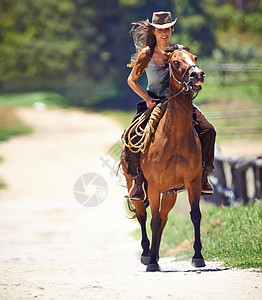 爱室外 一个美丽的年轻女牛仔骑马的动作镜头 (笑声)图片