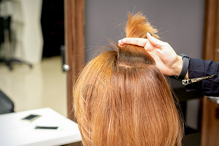 美发师在女性头发的手指间握着一根线 在美发沙龙检查年轻女子的头发理发梳子客户发型成人美容师治疗染料划分护理图片