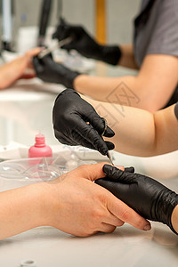 修指甲师在美甲沙龙把剪刀上戴保护手套的女性钉子上的切片除去温泉工具食指女士皮肤表皮健康服务手指护理图片