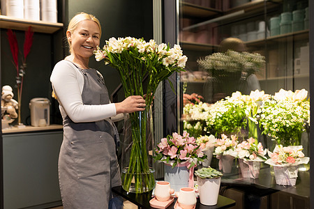 花店雇员在冰箱旁边用鲜花送花花的鲜花作为花束图片