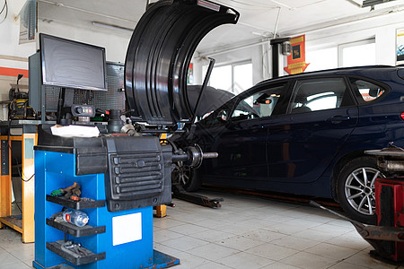 一辆用于平衡车轮和修理汽车轮胎的机器的照片 在一辆蓝色客车的背景下 在一个服务站 在一个开放式引擎盖的修理中兜帽轮子平衡轮平衡轮图片