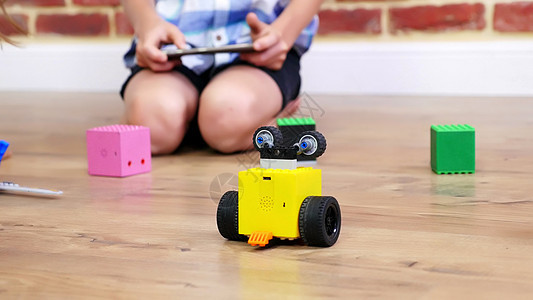 特写 无线电控制的机器人在地板上移动 小天才 孩子们玩电子机器人 汽车 无线电控制的现代玩具 游戏行业的新技术图片