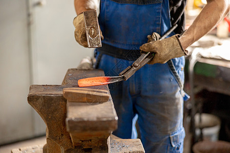 特写加热金属和铁砧的视图 铁匠在锻造中手工制作金属产品的生产过程 铁匠用锤子锻造金属 金属工业 古老的职业精神工艺男性制造业工人图片