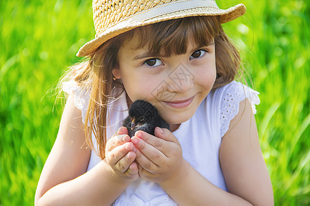 孩子手里握着一只鸡 有选择的专注花园小鸡宏观女孩鸭子帽子喜悦食物婴儿关爱世界高清图片素材