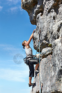 肾上腺素将她推向高峰会 一位年轻女子爬上岩石脸顶 与蓝天对立女性肌肉女士山脉乐趣天空旅行训练成人运动图片