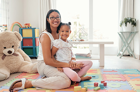一个快乐的母亲和孩子在游戏室里玩教育积木的肖像 女人的幸福 关怀和微笑 抱着她的女孩 坐在五颜六色的房间里 家里有玩具图片