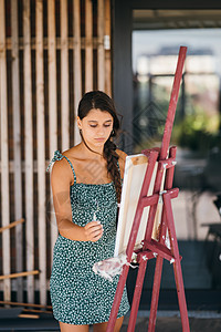 年轻女艺术家涂画画布上有毛片女性女孩刷子杰作工作室艺术工作职业画家帆布图片
