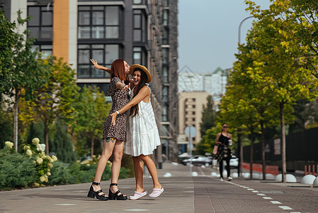 两位朋友在街上拥抱的愉快相会女性街道享受女孩们幸福友谊女士快乐青少年微笑图片