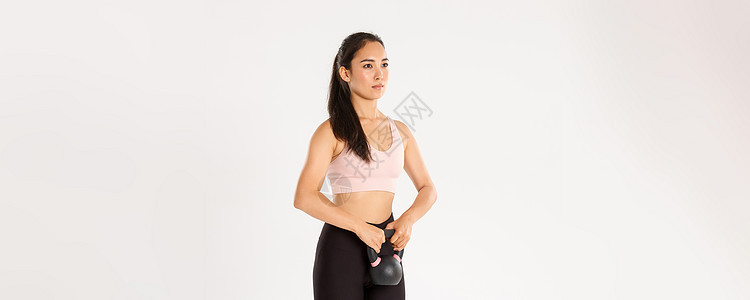 运动 健康和积极的生活方式理念 侧视严肃而专注的亚洲强壮健身女孩 女运动员在健身房锻炼 用壶铃锻炼蹲下 站立白色背景成人下蹲女性图片